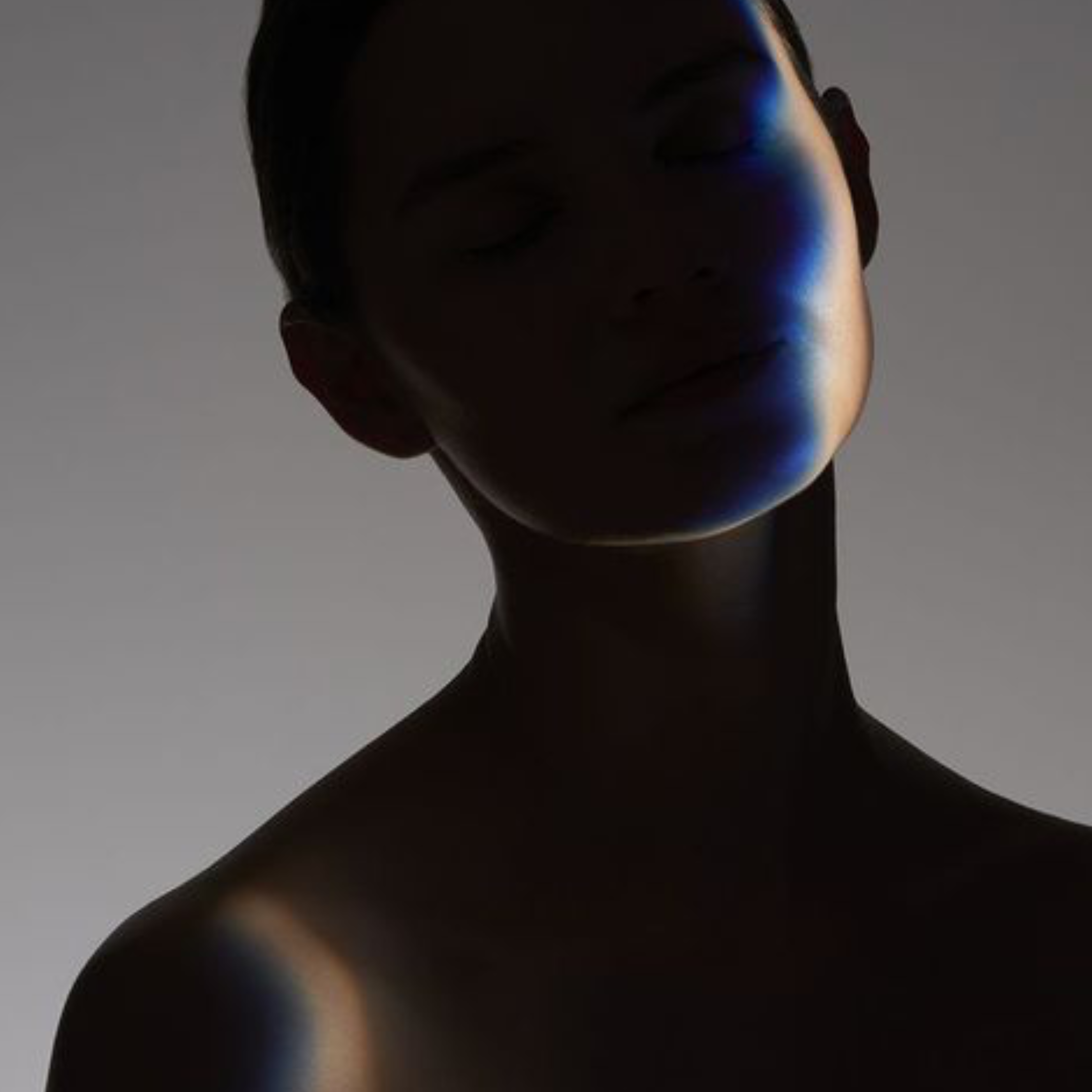 Dark image of a face and upper shoulders of a person against a gray background