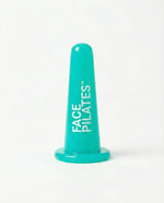 A turquoise plastic cone-shaped facial exercise device with the words 'FACE PILATES' printed vertically in white, set against a plain white background.